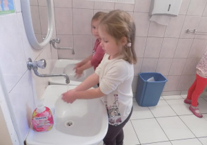 Róża i Marysia ćwiczą prawidłowe mycie rąk przy umywalce.